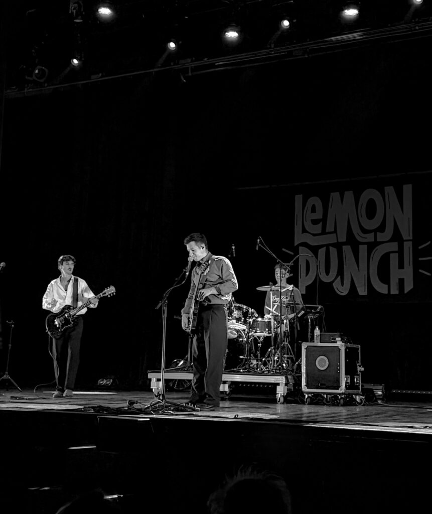 Lemon Punch sur la scène de l’Espace des Arts des Pavillons-sous-Bois, devant la bannière du groupe